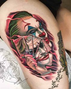 a woman's thigh with tattoos on it and a joker face holding playing cards