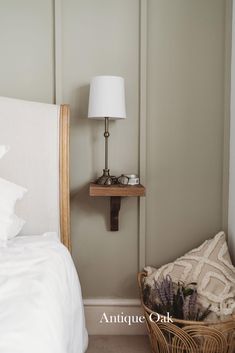 a white bed sitting next to a lamp on top of a wooden shelf in a bedroom