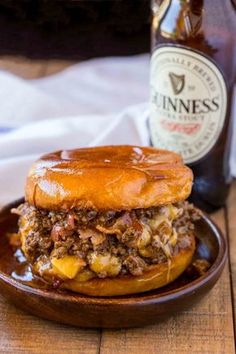 a beef sandwich on a wooden plate next to a bottle of beer and a napkin