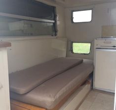 the inside of a camper with mattresses and cabinets