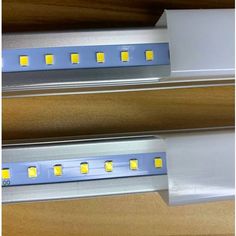 two led strip lights on top of a wooden table next to each other with white and yellow light