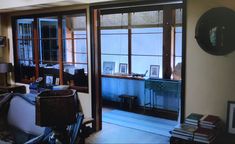 a living room filled with lots of furniture next to a window covered in books and pictures