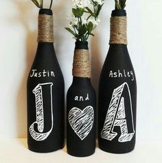 three wine bottles decorated with chalk and twine, one has the word love written on it