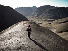 a man hiking up the side of a mountain with mountains in the backgroud