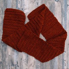 a pair of red knitted mittens sitting on top of a wooden floor