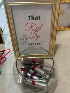 there is a glass bowl filled with silver and red crayons in front of a sign that reads, that read lip classic