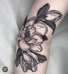 a black and white flower tattoo on the right arm, with leaves around it's petals