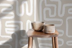 two bowls sitting on top of a wooden table in front of a wall with white paint