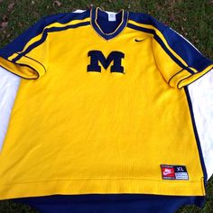 a yellow and blue michigan football jersey laying on the ground with it's sleeves folded