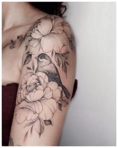 a woman's shoulder with flowers and a bird on it