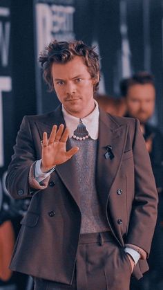 a man wearing a suit and tie making the vulcan sign