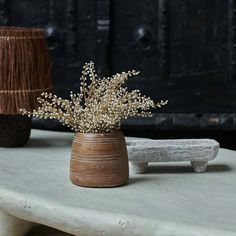 a vase with some flowers in it sitting on a table next to a wooden object