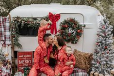 a man and woman in red pajamas sitting on the back of a camper with their child