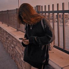 a woman standing on a bridge looking at her cell phone while wearing tights and stockings