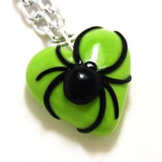 a green heart shaped pendant with a black spider on it