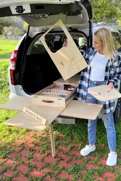 a woman standing next to a white car with its trunk open and boxes in the back