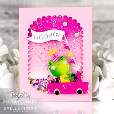 a card with a frog driving a pink car on it's side and flowers in the background