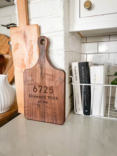 a wooden cutting board sitting on top of a kitchen counter next to a white vase