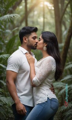 a man and woman are kissing in the middle of a forest with sun shining through the trees