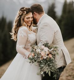 a bride and groom standing on top of a mountain