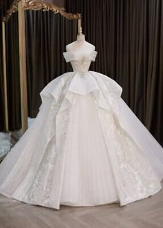 a white wedding dress on display in front of a gold framed mirror and black curtains