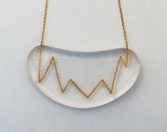 a white necklace with gold chains hanging from it's sides and an arrow on the side