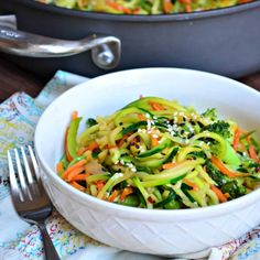 a close up of a bowl of food with broccoli and carrots in it