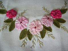 some pink flowers and green leaves on a white cloth