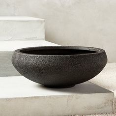 a black bowl sitting on top of cement steps next to a white stair case,