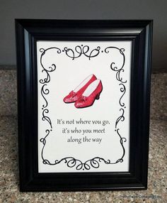 a red shoe is on display in a black frame with a white border and the words it's not where you go, it's who you meet along the way