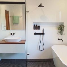 a white bath tub sitting next to a bathroom sink under a mirror and shower head