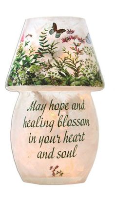 a ceramic lamp that has a quote on the bottom and flowers around it, with a butterfly