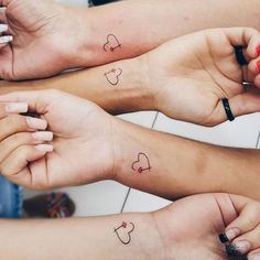 three people with matching tattoos on their arms holding hands in the shape of heart shapes