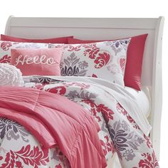 a bed with pink and white comforters and pillows