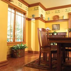 a dining room with yellow walls and wooden furniture, along with potted plants on the table