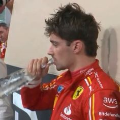 a man in a red racing suit brushing his teeth