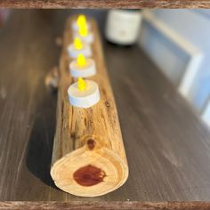 candles are lined up on a wooden stand with wax in them and yellow lights shining from the top