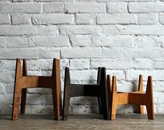 three wooden chairs sitting next to each other in front of a white brick wall and floor