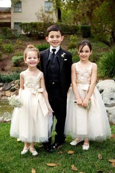 three young children dressed in formal wear standing next to each other on the grass outside