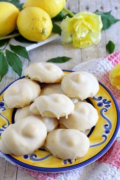 a yellow and blue plate filled with cookies on top of a table next to flowers