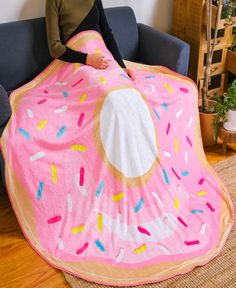 a woman sitting on a couch under a pink blanket with sprinkles