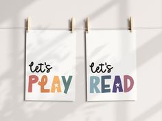 two posters hanging on clothes pins with let's lets play read written in multicolored letters