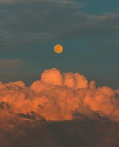 the moon is setting over some clouds in the evening sky with orange glow on it