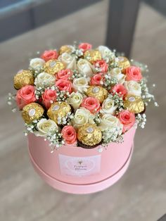 a pink box filled with lots of different types of flowers and gold foiled chocolates