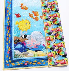 a quilted wall hanging with an ocean scene on it's side and fish in the water