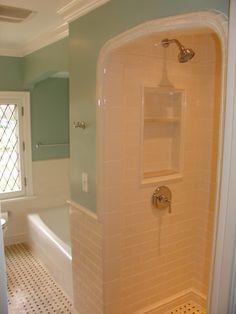 a bath tub sitting next to a toilet in a bathroom under a window with blue walls