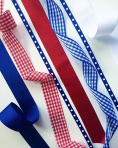 three different colored ties are laying next to each other on a white surface with red, white and blue ribbons