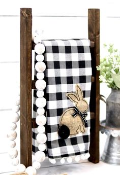 a black and white checkered towel holder with a bunny on it, sitting next to some flowers