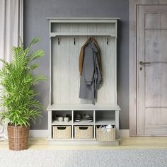 a white coat rack sitting next to a potted plant