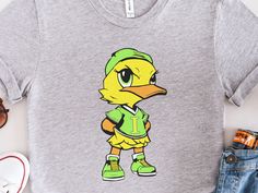 "Take the support of your child's softball team to a whole new level with this Issaquah Ducks Tee Shirt!  Featuring an originally designed iconic Issaquah Ducks logo across the chest, this shirt is a bold statement piece that's sure to turn heads. The Back features the \"Issaquah Ducks\" text in the team's colors of Yellow and Lime Green.  Whether you're cheering on the team from the stands, hitting the gym, or just lounging around at home, this Issaquah Ducks shirt is the perfect choice. Join t Fan Apparel Tops With Mascot For Sports Events, Sports Fan Tops With Mascot, Green Pre-shrunk Sports Shirt, Sporty Mascot Top For Fan Gear, Sporty Mascot Tops For Sports, Sporty Mascot Top For Sports, Sporty Tops With Mascot For Fan Gear, Casual Mascot T-shirt For Fans, Sporty Tops With Heat Transfer Vinyl For Fans